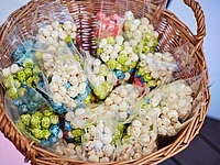 Wicker basket filled with cellophane bags of popcorn in various colors including white, green, blue, and pink
