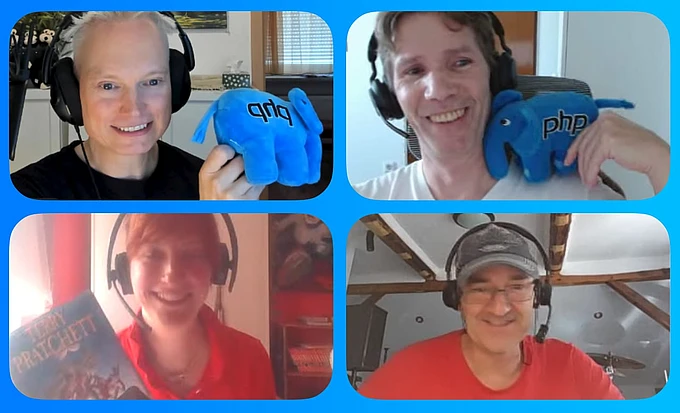 Four people wearing headphones smiling at camera, holding blue PHP mascot plushies in streaming setup