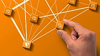 Wooden blocks with extension icons on orange background. One with the TYPO3 logo. A hand hold one block. White lines connect the blocks.