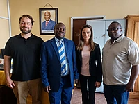 Four professionals standing together in an office with a portrait on the wall behind them