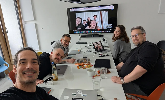 TYPO3 marketing sprint participants collaborating in a hybrid workshop in Berlin, with remote team members joining via video call on a large screen.