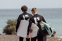 Two surfers carrying their surf boards to the ocean