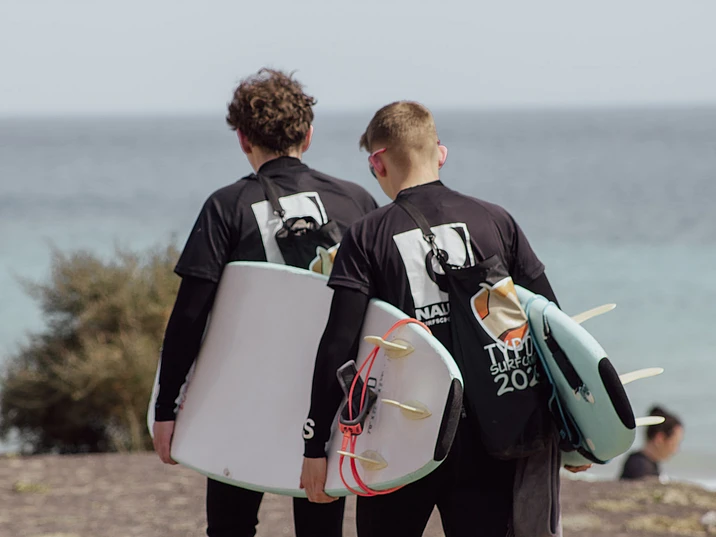 Two surfers carrying their surf boards to the ocean