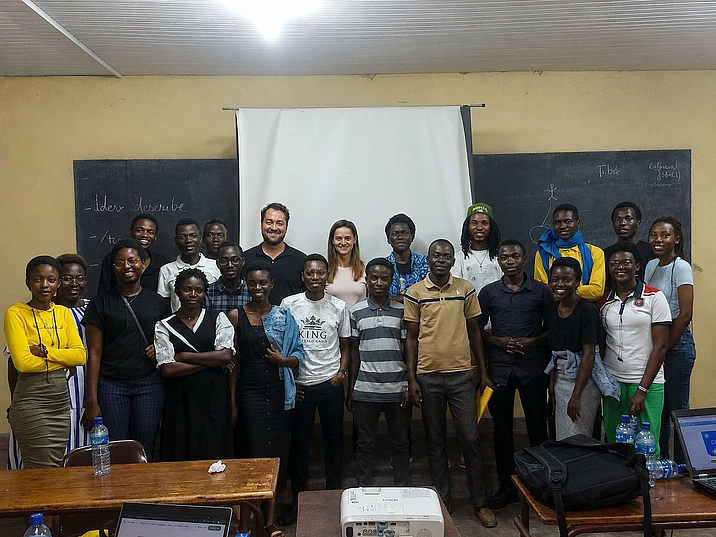 Group photo of diverse students and instructors in a classroom with blackboards and educational materials