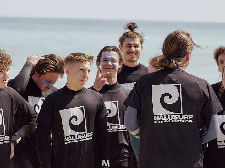 Group of surfers gathering for a surf lesson on the beach