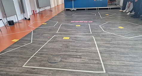 Taped floor sections with colored labels for a group activity.