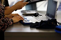 Hands operating a braille display connected to a laptop.