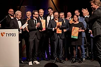 A group of people standing on stage holding awards and applauding.
