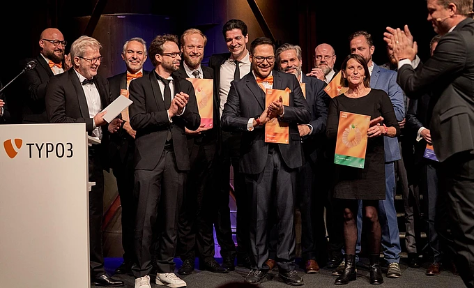 A group of people standing on stage holding awards and applauding.