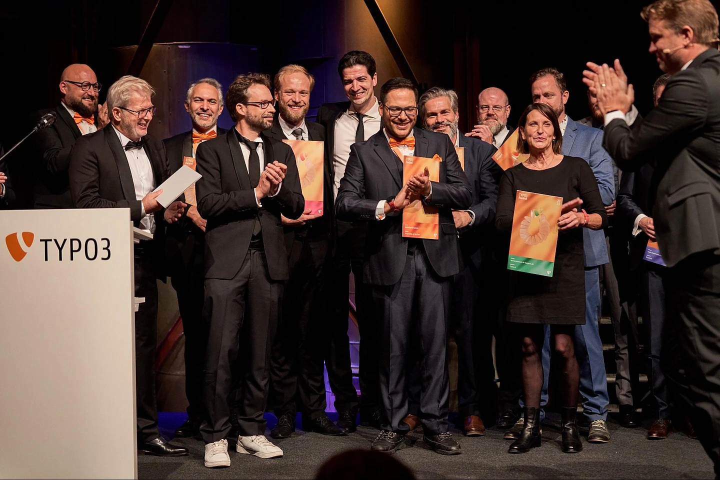 A group of people standing on stage holding awards and applauding.