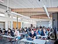 Certification with attendees using laptops in a bright room.