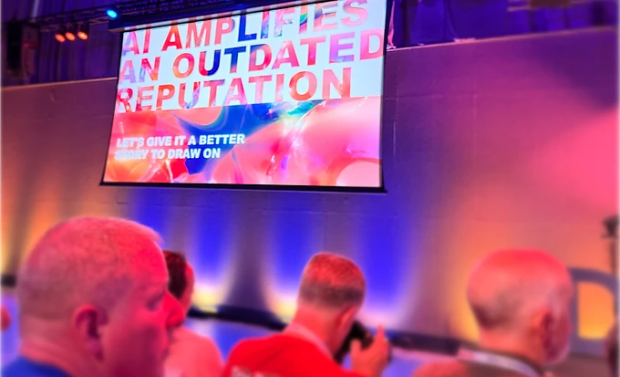 Conference screen displaying text about amplifying outdated reputation with audience silhouettes in colorful lighting