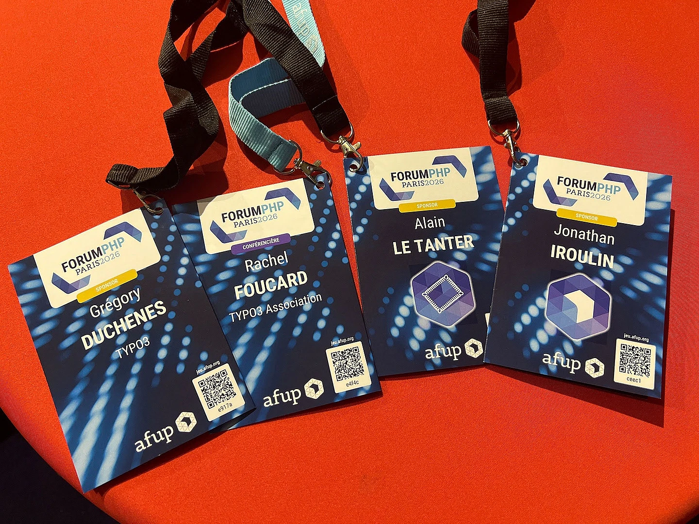 Four Forum PHP Paris 2026 conference badges with lanyards on orange background