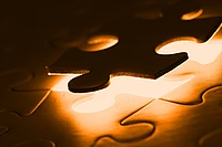 A close-up of a glowing puzzle with one piece being placed into an empty spot, illuminated with a warm, golden light.