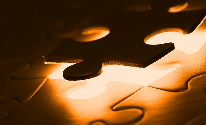 A close-up of a glowing puzzle with one piece being placed into an empty spot, illuminated with a warm, golden light.