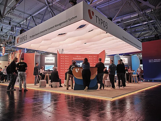 TYPO3 booth at DMEXCO featuring multiple partner companies, with attendees networking and engaging at the open exhibition stand.