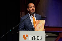 Jonathan Iroulin from Talan Solutions accepts award for the TYPO3 Website of the Year on stage.