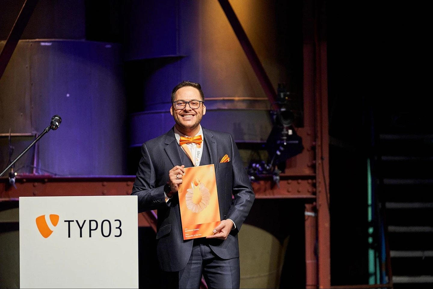 Abdulhamid Kwieder accepts the award for the TYPO3 Personality of the Year on stage.