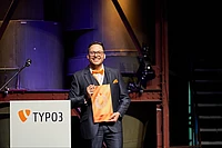Abdulhamid Kwieder accepts the award for the TYPO3 Personality of the Year on stage.