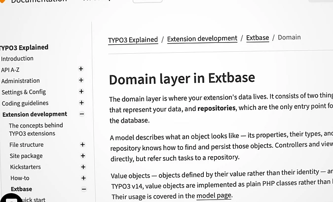 A computer screen displays documentation for TYPO3, specifically about the Domain layer in Extbase, with navigation links on the left and descriptive text on the right.