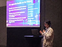 Speaker presenting risk management approach on screen with bullet points and bar chart during conference
