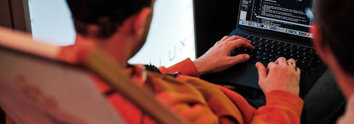 Person coding on a laptop in a lounge chair.