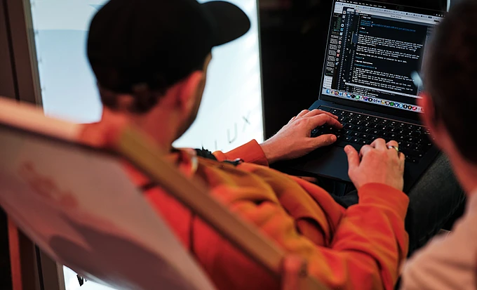 Person coding on a laptop in a lounge chair.