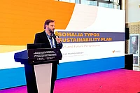Man speaking at podium presenting Somalia TYPO3 Sustainability Plan at digital government conference